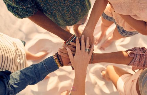 A group of diverse people coming together, holding hands in unity.