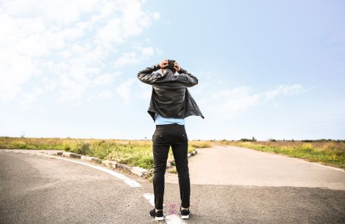 Person standing at a crossroad, representing choices and uncertainty.