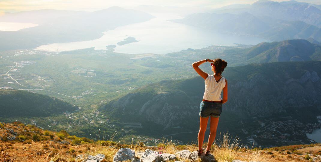 A silhouette standing atop a hill, looking towards a vast expanse, embodying the act of envisioning dreams.