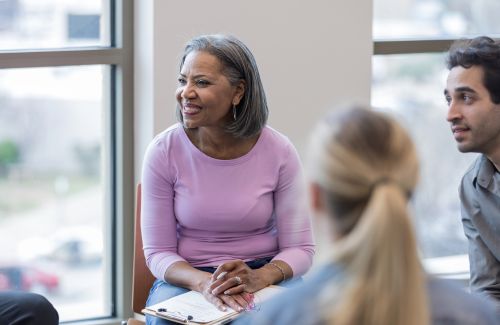 A person saying no with a warm smile, surrounded by supportive friends.