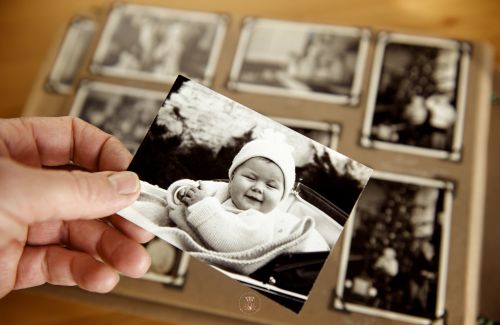 An adult holding a photograph of themselves as a child, representing the connection to the inner child.