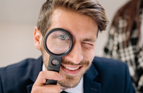 A person holding a magnifying glass, focusing on a clear goal.