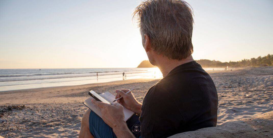 A person writing in a journal, bathed in soft morning light.