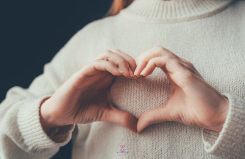 Hands forming a heart shape on a body