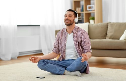 A person in a meditation posture with a smile on his face.