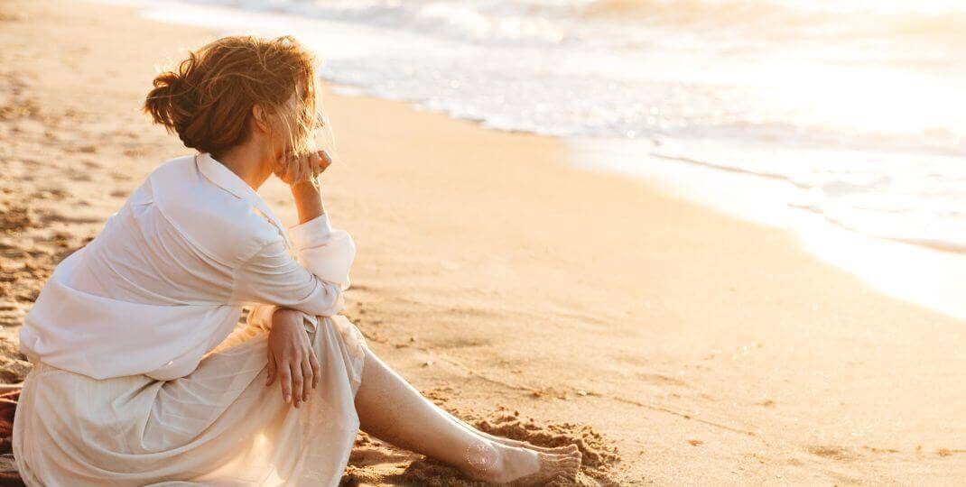 Self-Questioning - A person sitting by calm sea, deep in thought.