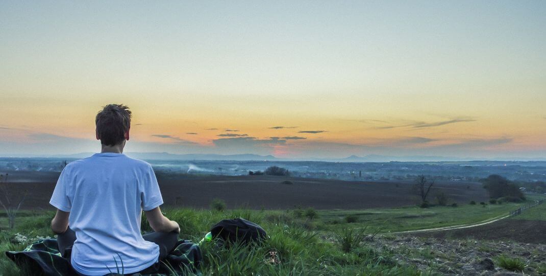 Spiritual Growth in Relationships - Image of a person meditating near a calm lake at sunrise