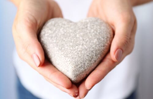 Learning from Experience - A close-up of hands holding a heart-shaped stone, symbolizing self-love and forgiveness.