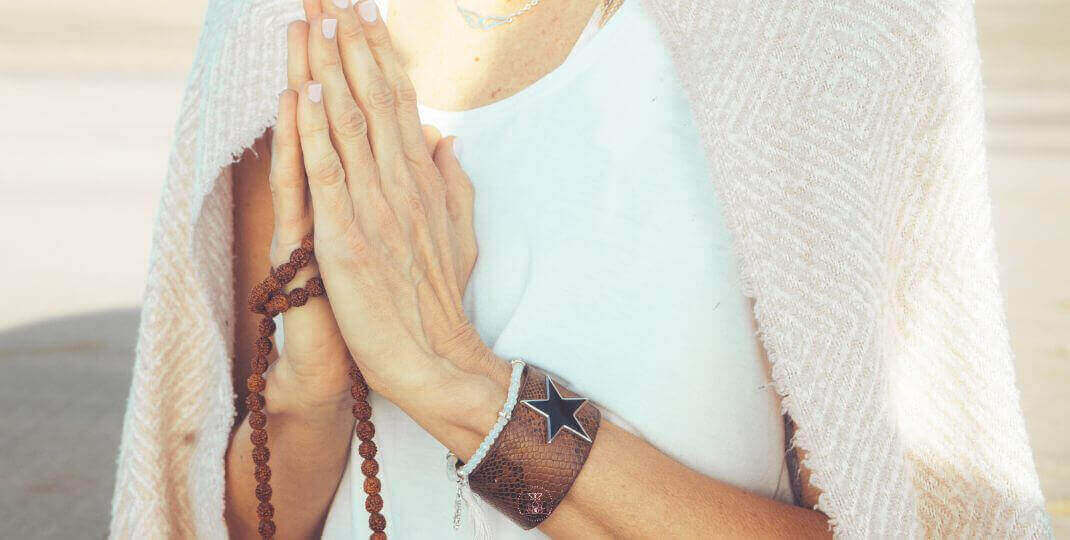 Take a Step Back - A close-up of hands holding mala beads