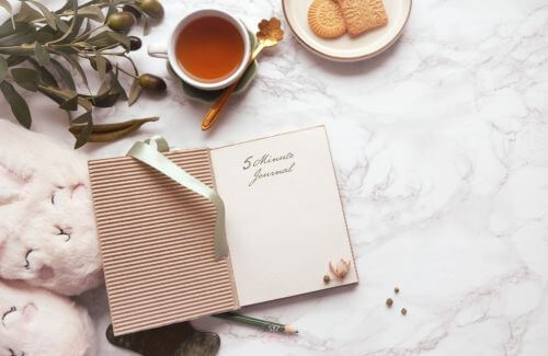 What You Focus on Becomes Reality - A serene workspace with a journal, a cup of tea, and motivational quotes.