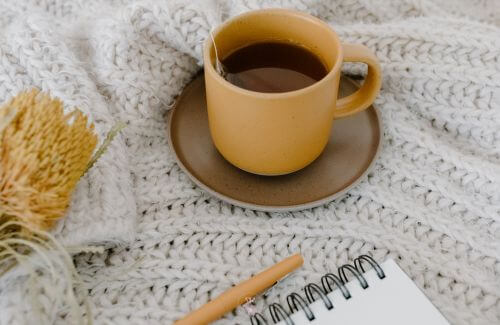 Ways to Soothe Overwhelm Naturally - A cup of herbal tea next to a journal