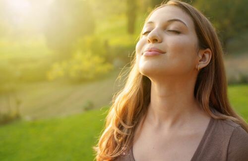 Ways to Soothe Overwhelm Naturally - A woman taking a deep breath with eyes closed